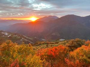 a sunset in the mountains with the sun setting at Top Cloud Villa in Renai