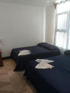 two beds in a room with white towels on them at Pura vida apartments in Quepos