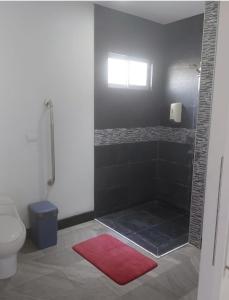 uma casa de banho com um chuveiro, um WC e um tapete vermelho em Pura vida apartments em Quepos