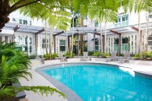 a swimming pool with palm trees in front of a building at Emerald Noosa in Noosa Heads