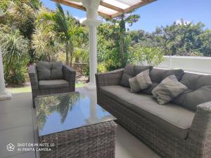 eine Couch und zwei Stühle auf einer Veranda in der Unterkunft villa Areca in Saint-Joseph