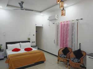 1 dormitorio con 1 cama con almohadas rojas y 2 sillas en Telma Beach Homestay, en Mararikulam
