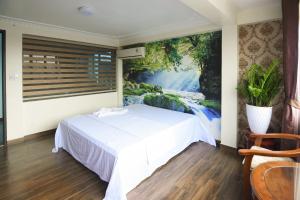 ein Schlafzimmer mit einem weißen Bett und einem Gemälde an der Wand in der Unterkunft HAPPY GUEST HOUSE in Haiphong