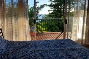 a bedroom with a bed and a view of a balcony at SUNSETVIEW, studio, private beach, amazing swim & sunset in Haapiti