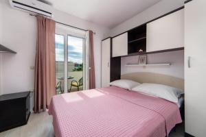 - une chambre avec un lit rose et un balcon dans l'établissement Apartments Divna, à Baška Voda