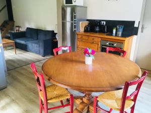 een houten tafel met rode stoelen en een keuken bij Gite Le Bois aux Moines in Lavaré