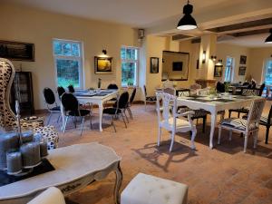 una sala da pranzo con tavoli, sedie e finestre di Hotel & Ferienpark Fleether Mühle a Mirow