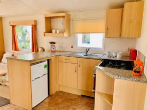 a kitchen with wooden cabinets and a white refrigerator at Devon Barnstaple Self Catering Accommodation Tarka Holiday Park, A14 Free Wi-Fi Spacious Tarka Holiday Park sleeps 5 Pets allowed Static Caravan home Devon EX31 4AU just 6 miles from Saunton Sands in Barnstaple
