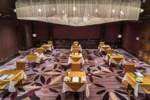 InterContinental Dhaka, an IHG Hotel في داكا: غرفة طعام بها طاولات وثريا كبيرة