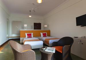 ein Hotelzimmer mit 2 Betten und 2 Stühlen in der Unterkunft Sea Green Hotel in Mumbai