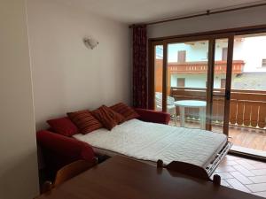 a bedroom with a bed and a balcony with a table at Monolocale Campodolcino in Campodolcino