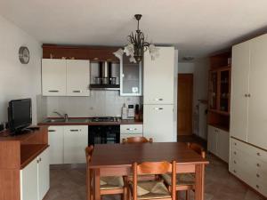 a kitchen with white cabinets and a wooden table at Monolocale Campodolcino in Campodolcino