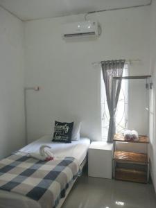 a small bedroom with a bed and a window at Pigeon House Nusa Dua in Nusa Dua
