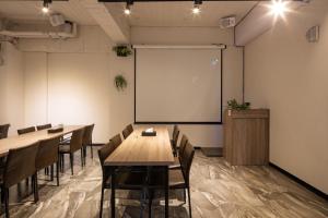 uma sala de aula com mesas e cadeiras e um quadro branco em Hotel Brown - Chihkan Branch em Tainan