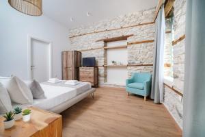 een slaapkamer met een bakstenen muur en een bed en een blauwe stoel bij Hibiscus Villa in Theológos