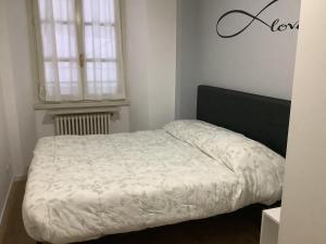 ein weißes Bett in einem Zimmer mit Fenster in der Unterkunft Lella's Home in Como