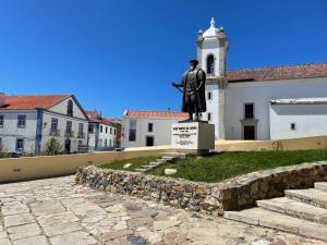 uma estátua de um homem parado em frente a um edifício em Maré Baixa em Sines