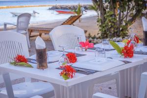 un tavolo bianco con sedie bianche e fiori su una spiaggia di Summer Vibes Beach Front a Rasdhoo