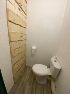 ein Badezimmer mit einem weißen WC und einer Holztür in der Unterkunft Appartement aux pieds des pistes ! in Les Angles