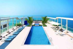 a resort swimming pool with chairs and the ocean at Pacific rak in Ras al Khaimah