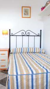 a bed with a blue and yellow striped comforter at Casa El Campanario del Caminito del Rey in Valle de Abdalagís