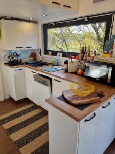 una cucina con mobili bianchi e una grande finestra di Sunset Tiny House GbR a Neuendorf Altre 31 foto