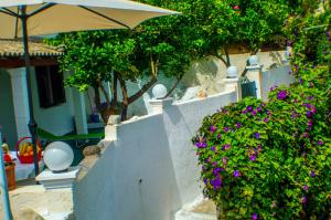 a white wall with purple flowers and an umbrella at Agathi Beach House (Black Rocks) in Agios Gordios