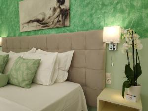 um quarto com uma cama com almofadas brancas e um candeeiro em Colourful apartments (Green Lagoon) em Argostoli