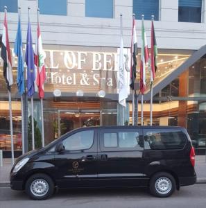 een zwart busje geparkeerd voor een gebouw met vlaggen bij Pearl of Beirut Hotel & Spa in Beiroet