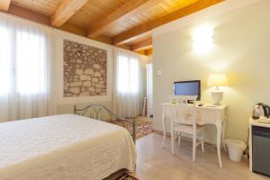 een slaapkamer met een bed, een bureau en een televisie bij Talamo Rooms in San Martino Buon Albergo
