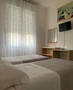 a hotel room with two beds and a television at Albergo Moderno in Modena