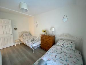 a bedroom with a bed and a dresser and a bed and a dresser at Ty-Nance Cottage in Caerphilly