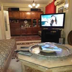 a living room with a tv and a table at Bel appartement proche de l'aéroport in Alger