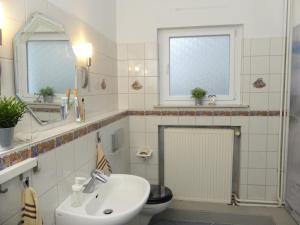 a bathroom with a sink and a toilet and two windows at Ferienhaus Strandlust in Butjadingen
