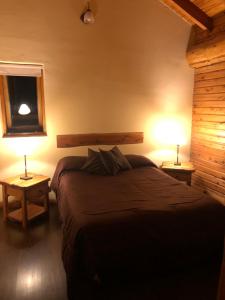 sypialnia z dużym łóżkiem i 2 lampami w obiekcie Cabañas Peumayen Meliquina w mieście Villa Meliquina