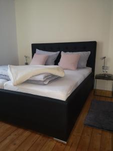 - un lit noir avec des oreillers roses et blancs dans l'établissement Apartment Sommer, à Winterberg