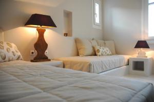 Habitación con 2 camas, lámpara y TV. en Chez Semiramis Aegean Pearl House for 8 persons 5'min from the beach, en Serifos Chora