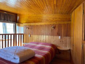 a bedroom with a bed in a wooden room at LE SAPORTA- Studios et Appartements meublés de tourisme in Le Lioran