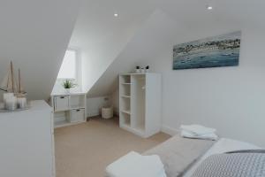 a white room with a bed and a mirror at Stylish Herne Bay apartment by the sea in Kent