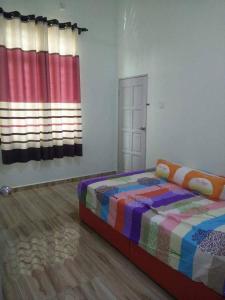 a bedroom with a bed with a colorful blanket and a window at D'Ombak Homestay Pantai Baru in Bachok