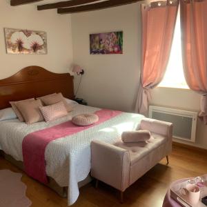 ein Schlafzimmer mit einem großen Bett und einem Stuhl in der Unterkunft Auberge Du Cheval Blanc in Beaumont-Pied-de-Boeuf