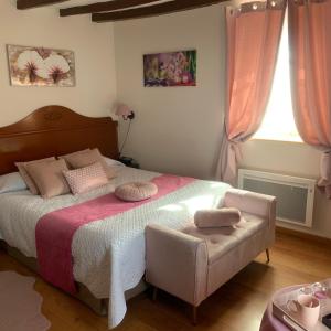 - une chambre avec un grand lit et une chaise dans l'établissement Auberge Du Cheval Blanc, à Beaumont-Pied-de-Boeuf