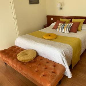 a bedroom with a large bed and a brown bench at Auberge Du Cheval Blanc in Beaumont-Pied-de-Boeuf