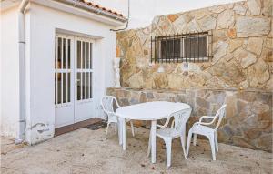een witte tafel en stoelen voor een stenen muur bij 8 Bedroom Lovely Home In Quintana Del Castillo in Quintana del Castillo