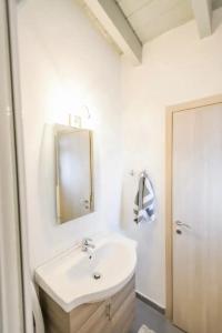 La salle de bains blanche est pourvue d'un lavabo et d'un miroir. dans l'établissement Yvonne's Stone House, à Arachova