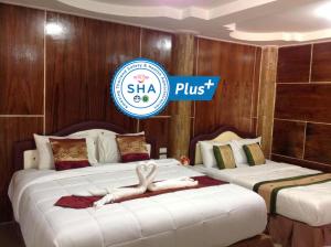 una habitación de hotel con dos camas con una mujer puesta en ellas en Ruan Mai Naiyang Beach Resort - SHA Plus, en Nai Yang Beach