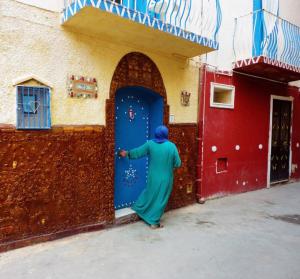 a woman standing in front of a blue door at Seacily house in Mazara del Vallo