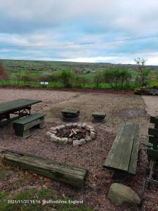 a fire pit with a picnic table and benches at Leek Camping Barns in Leek
