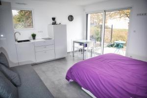 1 dormitorio con cama morada y cocina en L'à Côté, en Colmar