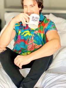 a man sitting on a bed drinking a cup of coffee at The Suite Cologne in Cologne